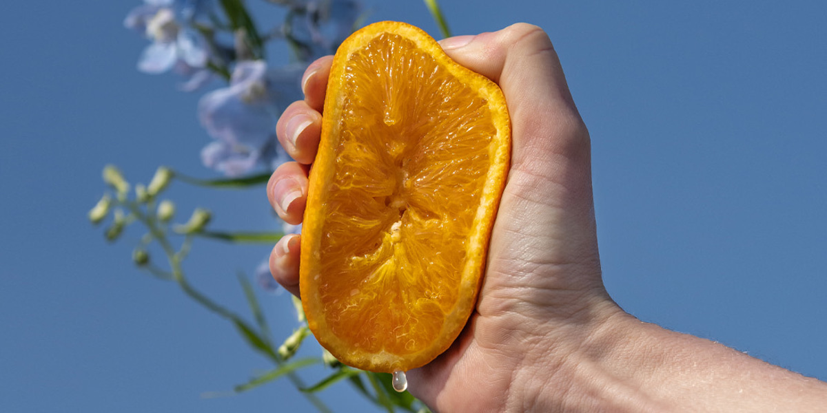 foto van een halve sinaasappel waar in geknepen wordt