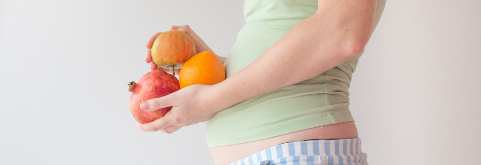 zwangere vrouw dat verschillende vruchten vasthoudt