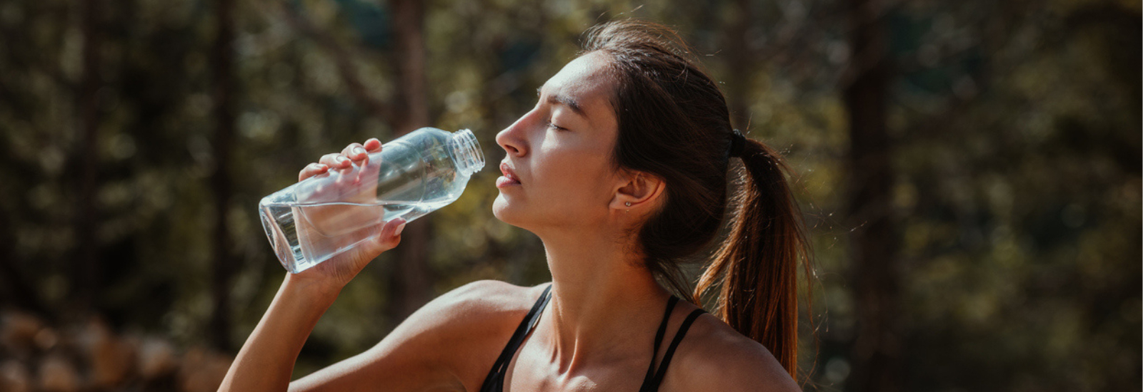 foto van vrouw die uit een glazen fles elektrolyten drinkt na het sporten