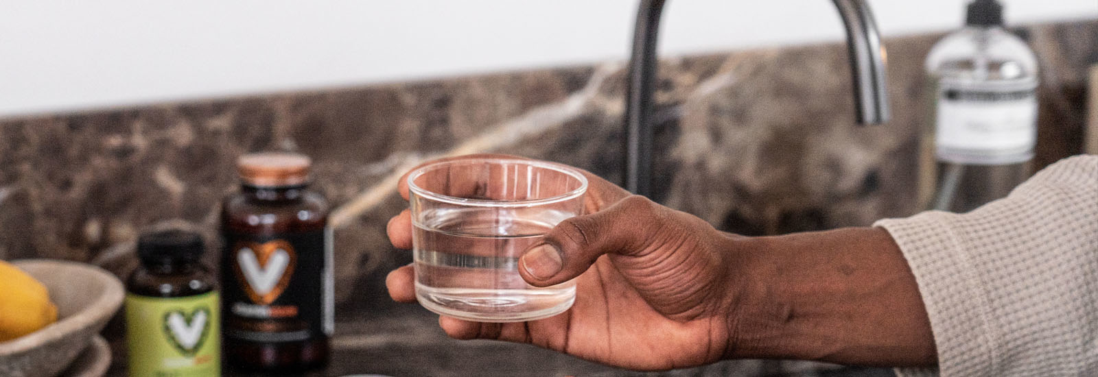 foto van hand met glas water en vitaminen op de achtergrond