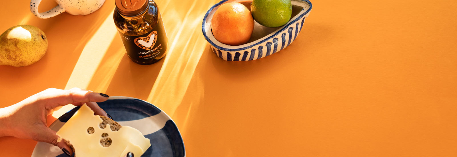 foto van broodje kaas en vitaminen op een oranje achtergrond