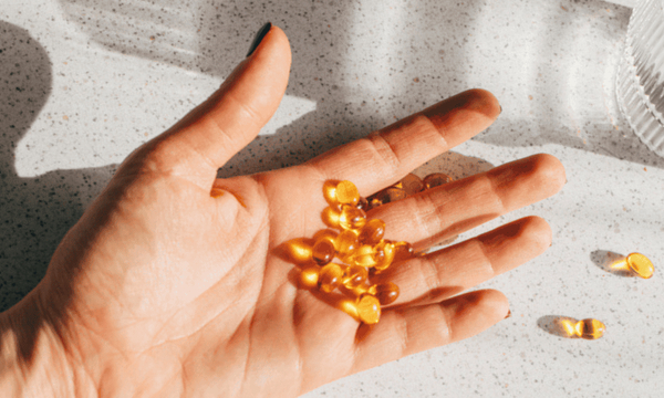 Afbeelding van foto van vitamine D capsules op een hand