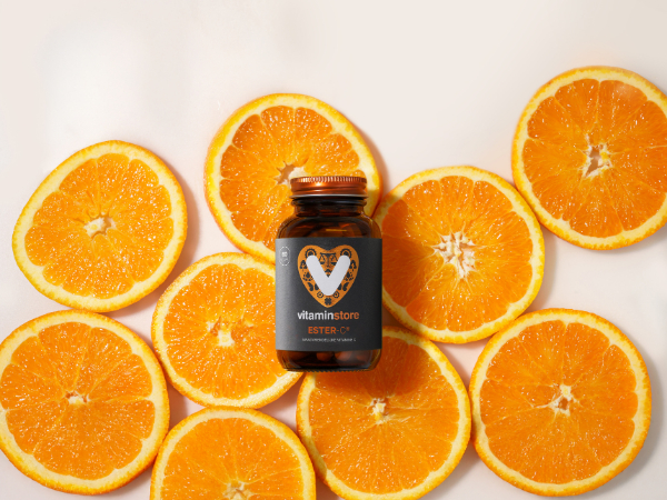 vitamin D supplement with small capsules in a hand against an orange background